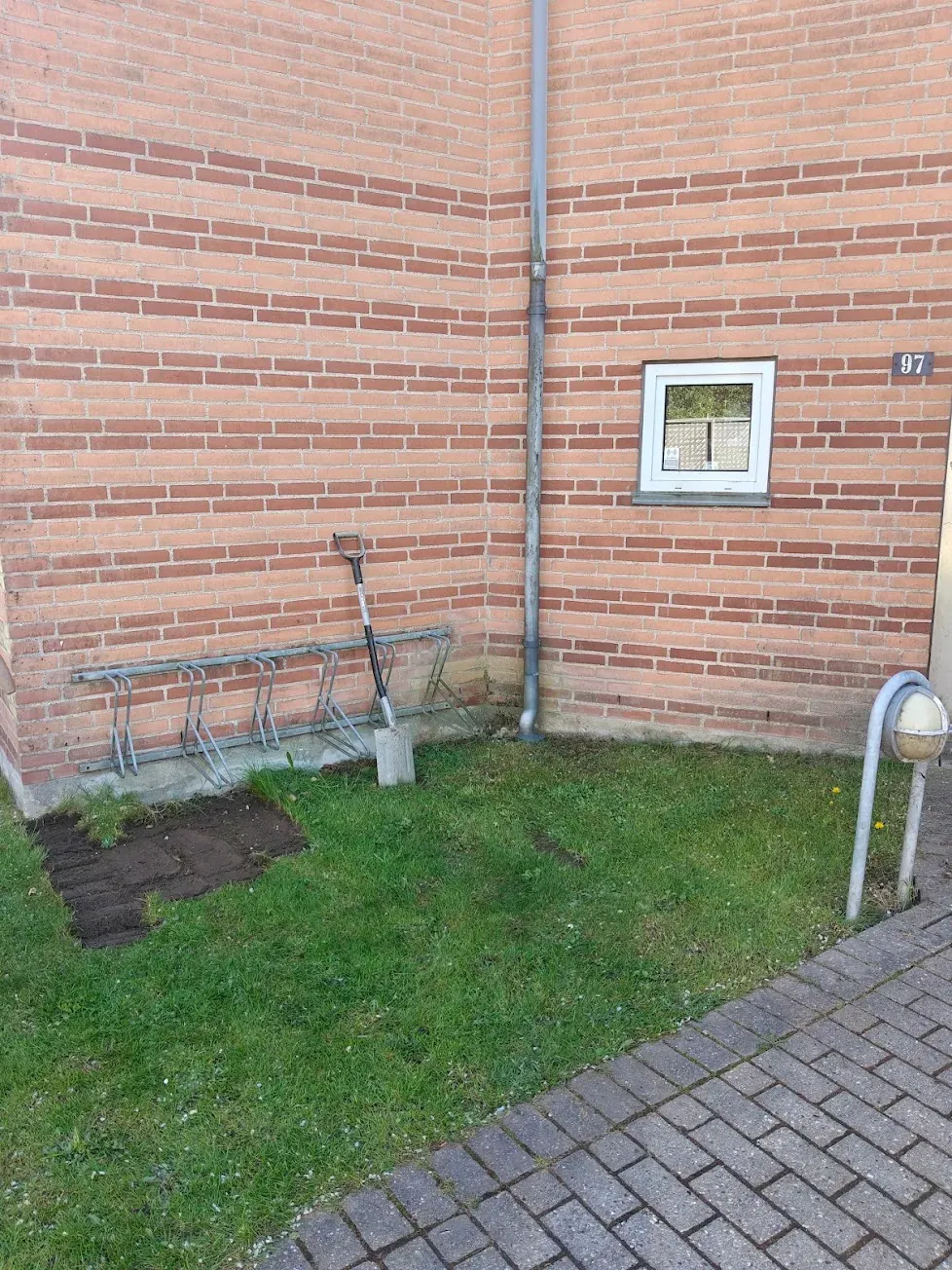 Brostenskant lagt mellem græsplæne og husmur